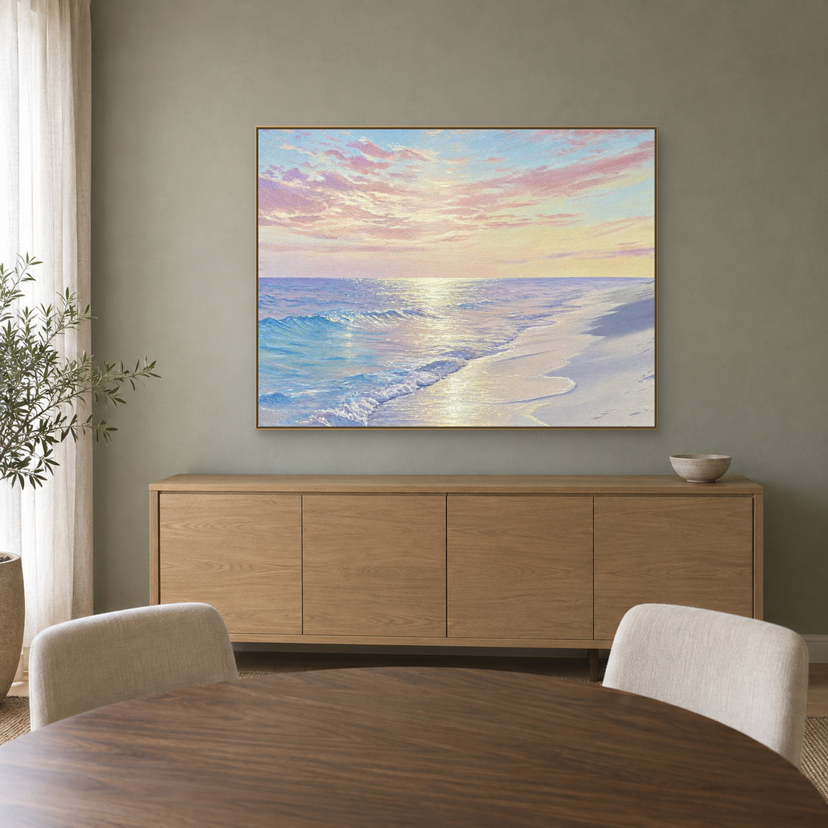 Pastel beach artwork in a champagne-tone frame above a light wood sideboard against a sage-green wall
