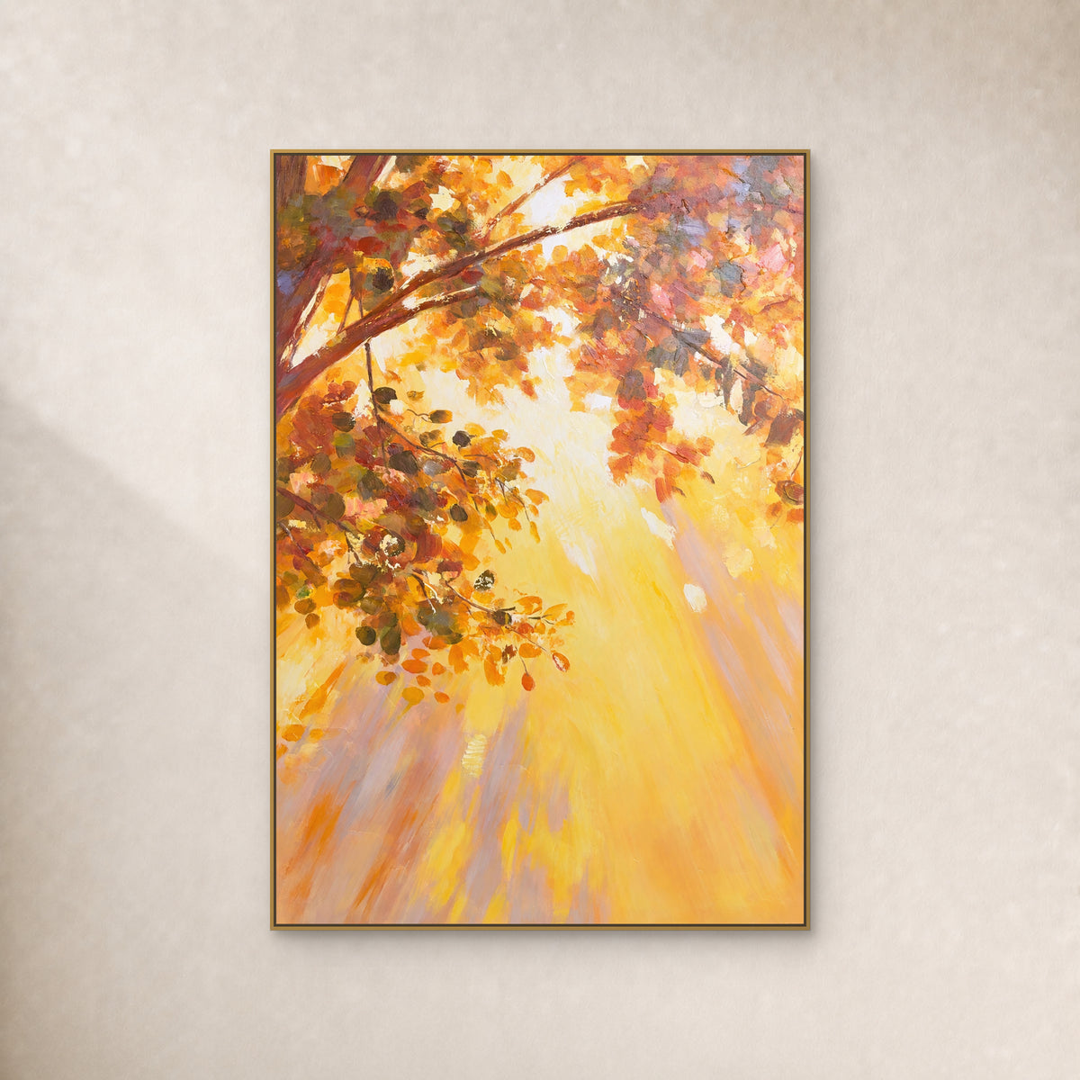 Vertical painting of amber autumn leaves and golden light in a slim gold floating frame on an ivory wall.