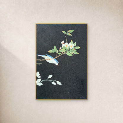 Blue-and-ivory bird and white blossoms on charcoal in a slim gold-tone frame against an ivory wall