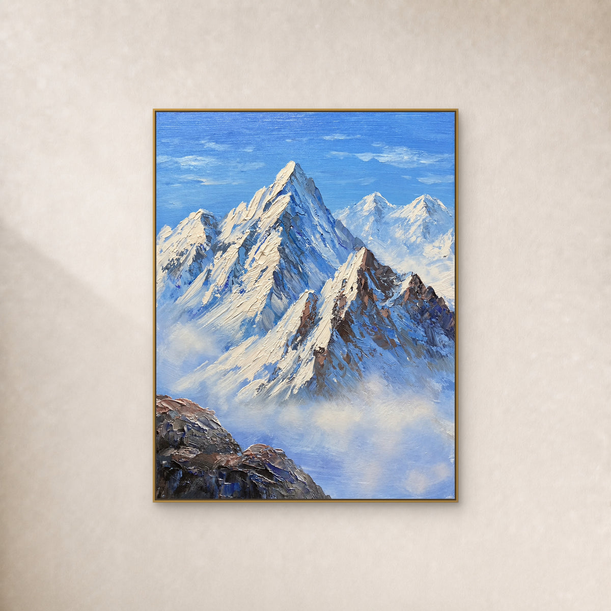 Blue and ivory snow mountain painting in a slim gold-tone floating frame on an ivory wall