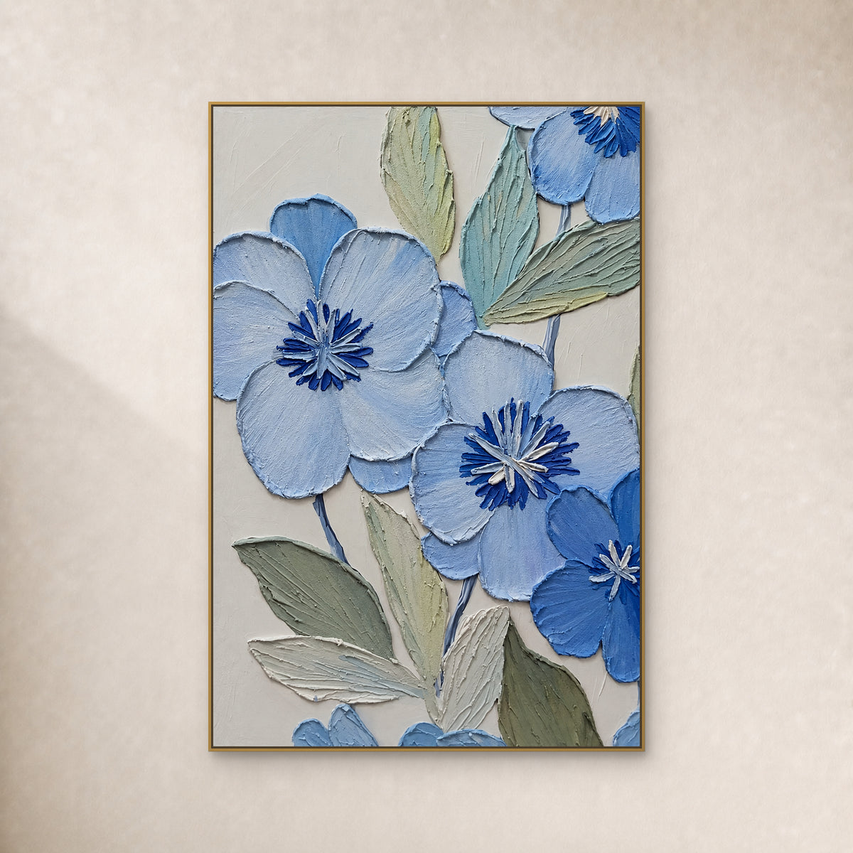 Powder-blue flowers with cobalt centres and sage leaves, in a thin gold-tone floating frame on an ivory wall