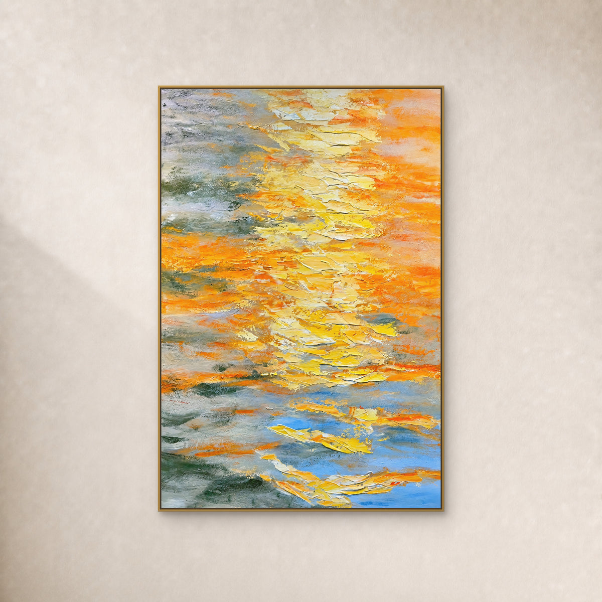 Yellow and orange abstract painting with pale overlapping ridges and blue-grey passages, in a thin gold-toned frame on an ivory wall