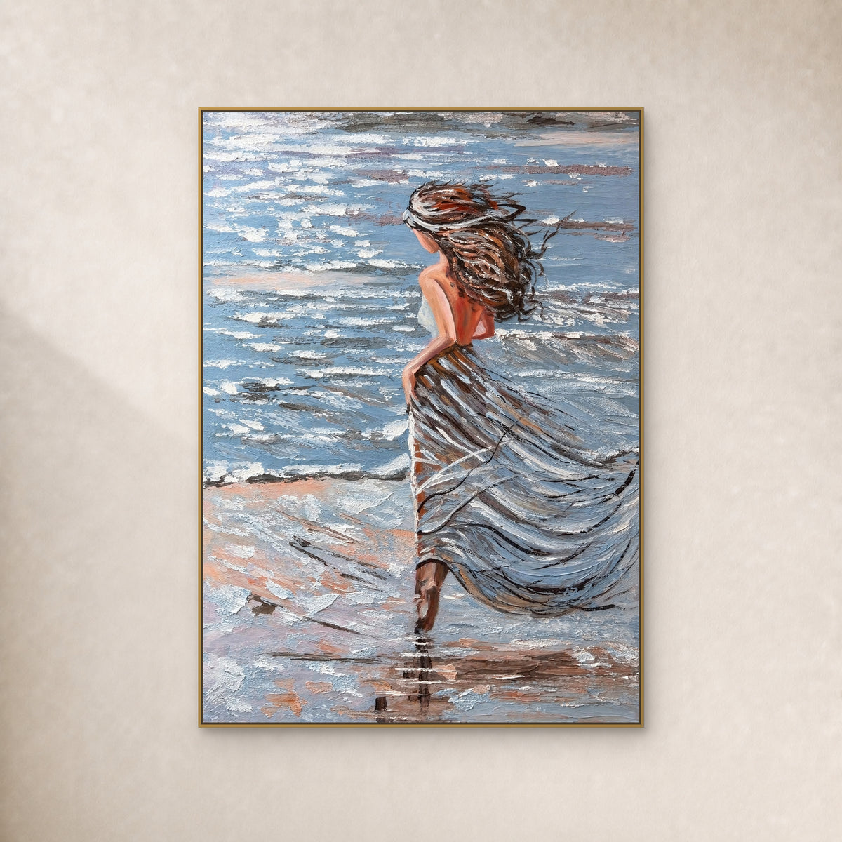 Femme aux cheveux au vent, en robe bleu-gris au bord de mer, dans un fin cadre flottant doré sur un mur ivoire