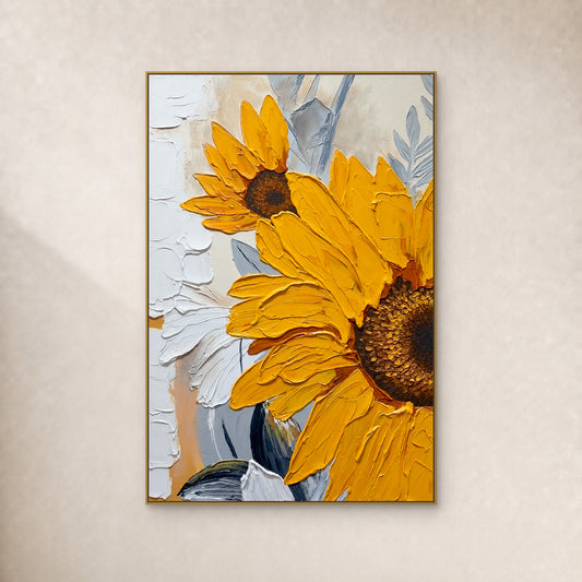Deux tournesols jaunes aux pétales en relief et au feuillage gris bleuté, dans un cadre fin doré sur un mur ivoire