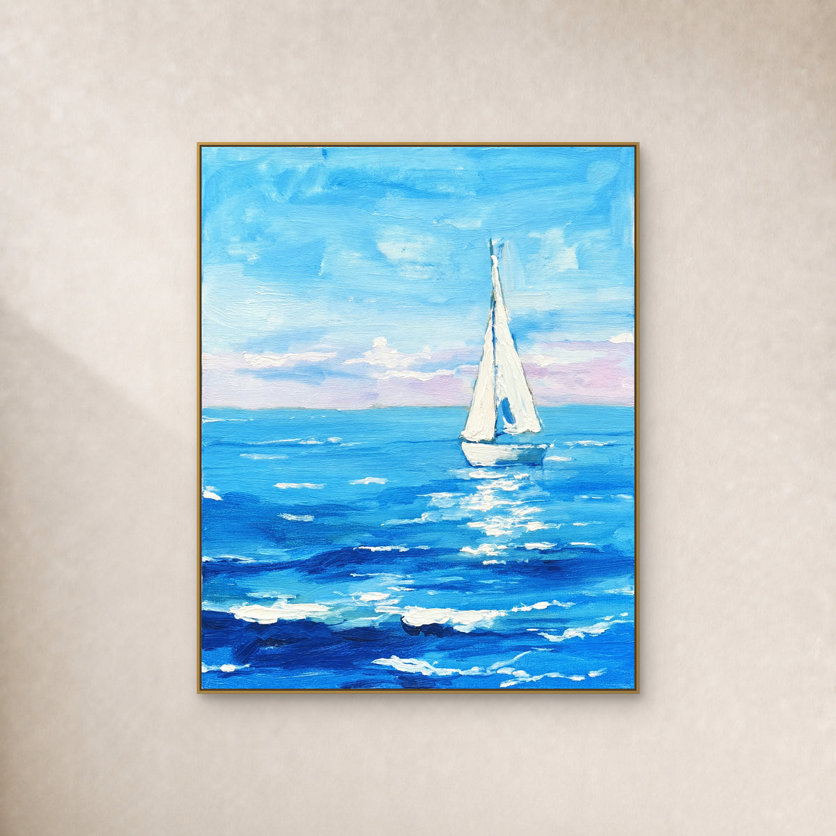 White sailboat on turquoise and cobalt waves beneath a blue sky, in a slim gold frame against an ivory wall.