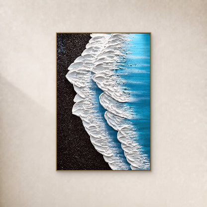 White surf and turquoise water beside a black shore, in a thin gold frame on an ivory wall