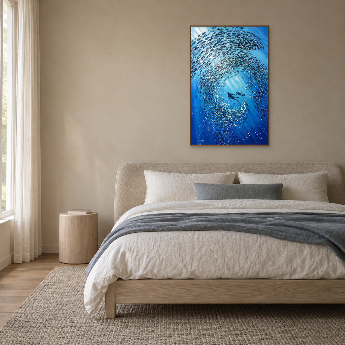 Tableau sous-marin bleu dans un cadre flottant ton chêne, centré au-dessus d’une tête de lit arrondie capitonnée et de draps gris