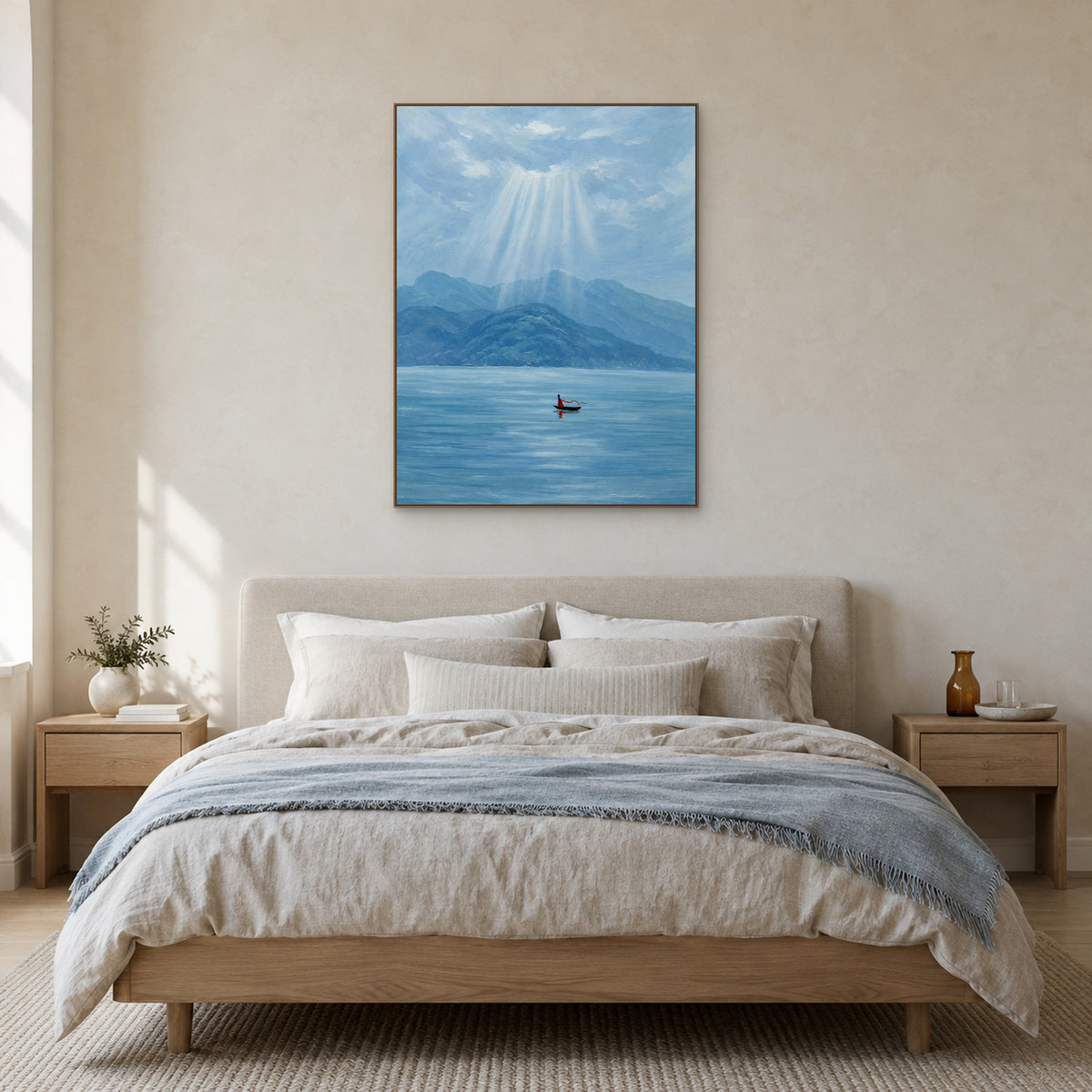 Blue mountain and lake painting in an oak-toned floating frame centred above a cream upholstered bed