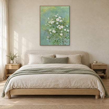 Tableau floral de jasmin dans un cadre ton chêne, centré au-dessus d’un lit en lin