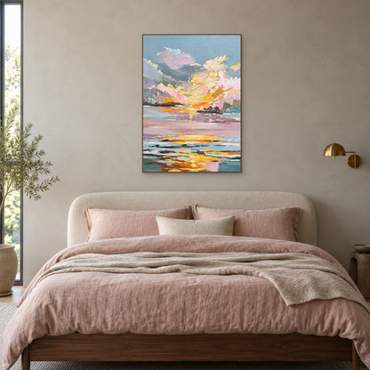 Vertical pink sunset painting in an oak-tone frame above a bed with blush linen
