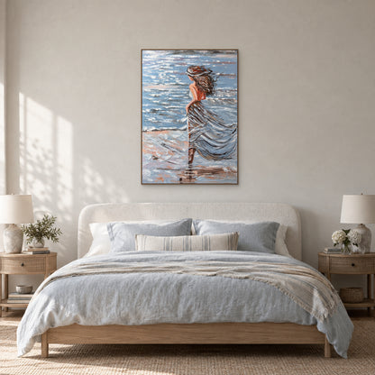 Tableau de femme au bord de mer dans un cadre flottant ton chêne, centré au-dessus d'une tête de lit ivoire arrondie et de linge bleu pâle