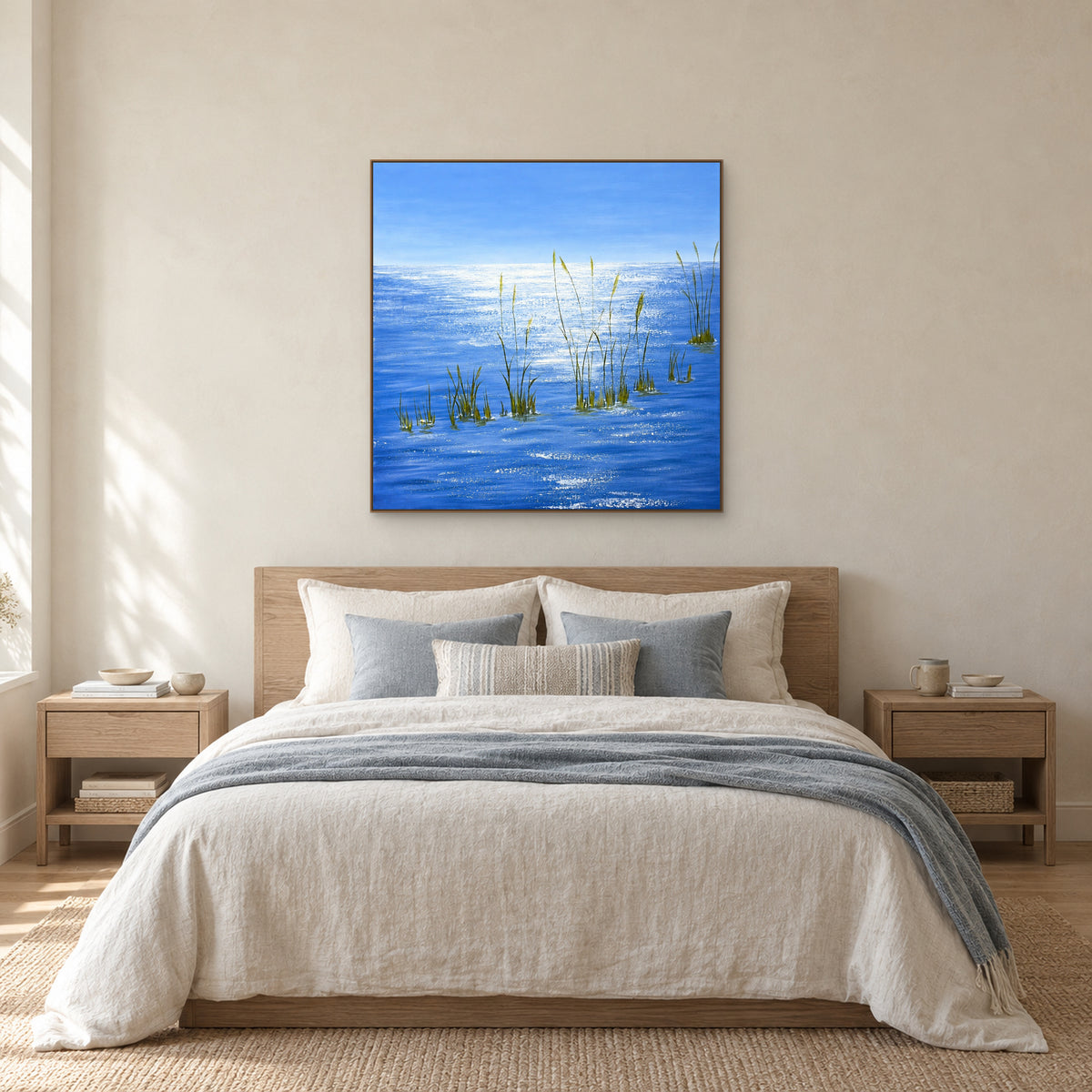 Tableau d’eau bleue dans un cadre aspect chêne, centré au-dessus d’un lit en lin clair