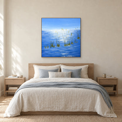 Tableau d’eau bleue dans un cadre aspect chêne, centré au-dessus d’un lit en lin clair