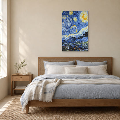 Tableau de village étoilé dans un cadre aspect chêne, centré au-dessus d’une tête de lit tressée et de linge bleu doux.