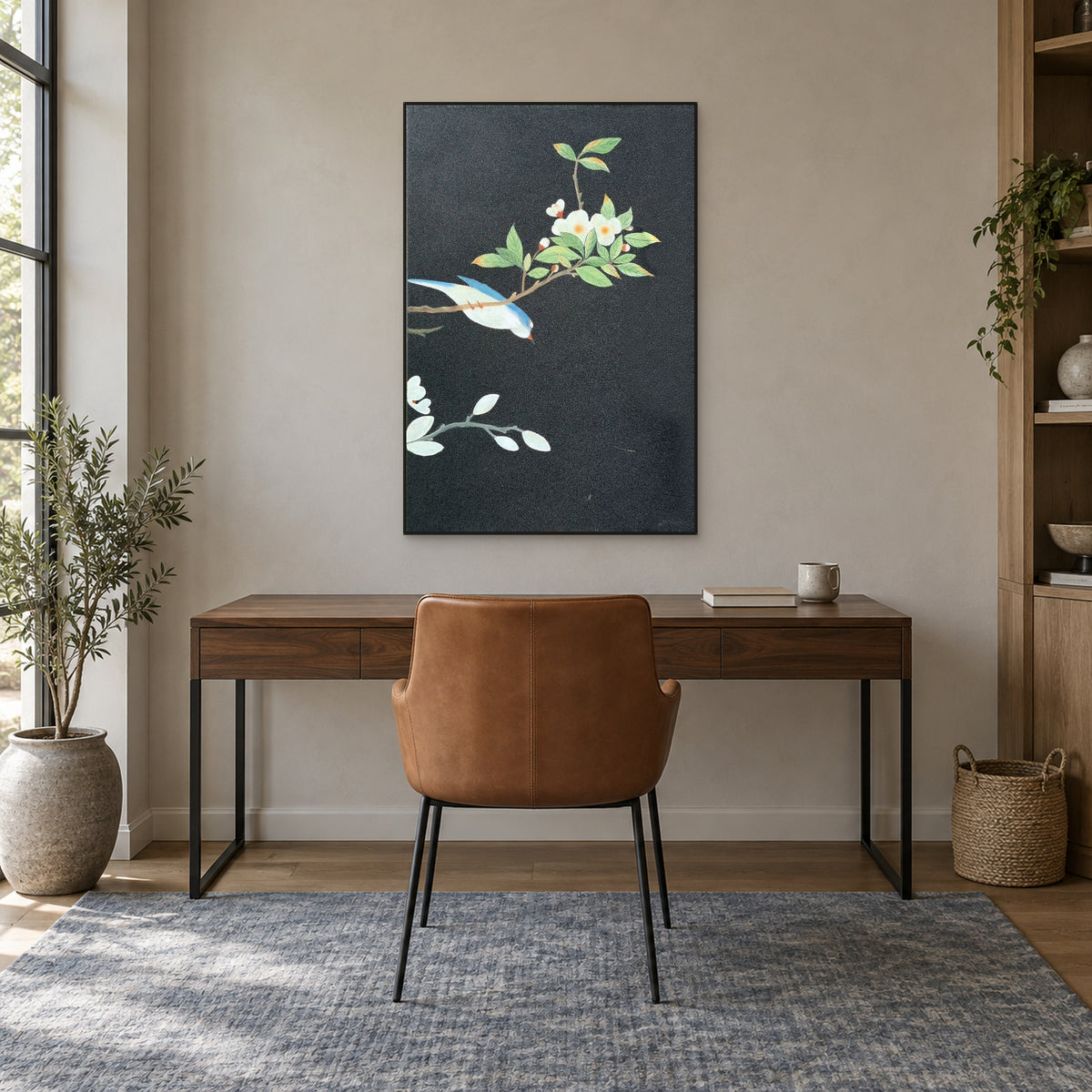 Black-framed blue bird painting centred above a walnut-tone desk and caramel chair