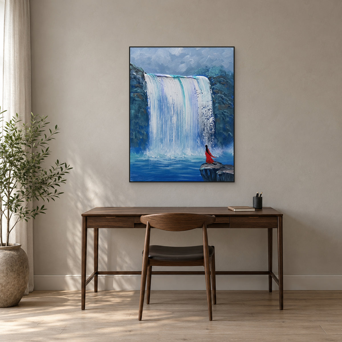 Vertical waterfall and red figure painting in a black frame above a walnut desk with a wooden chair.