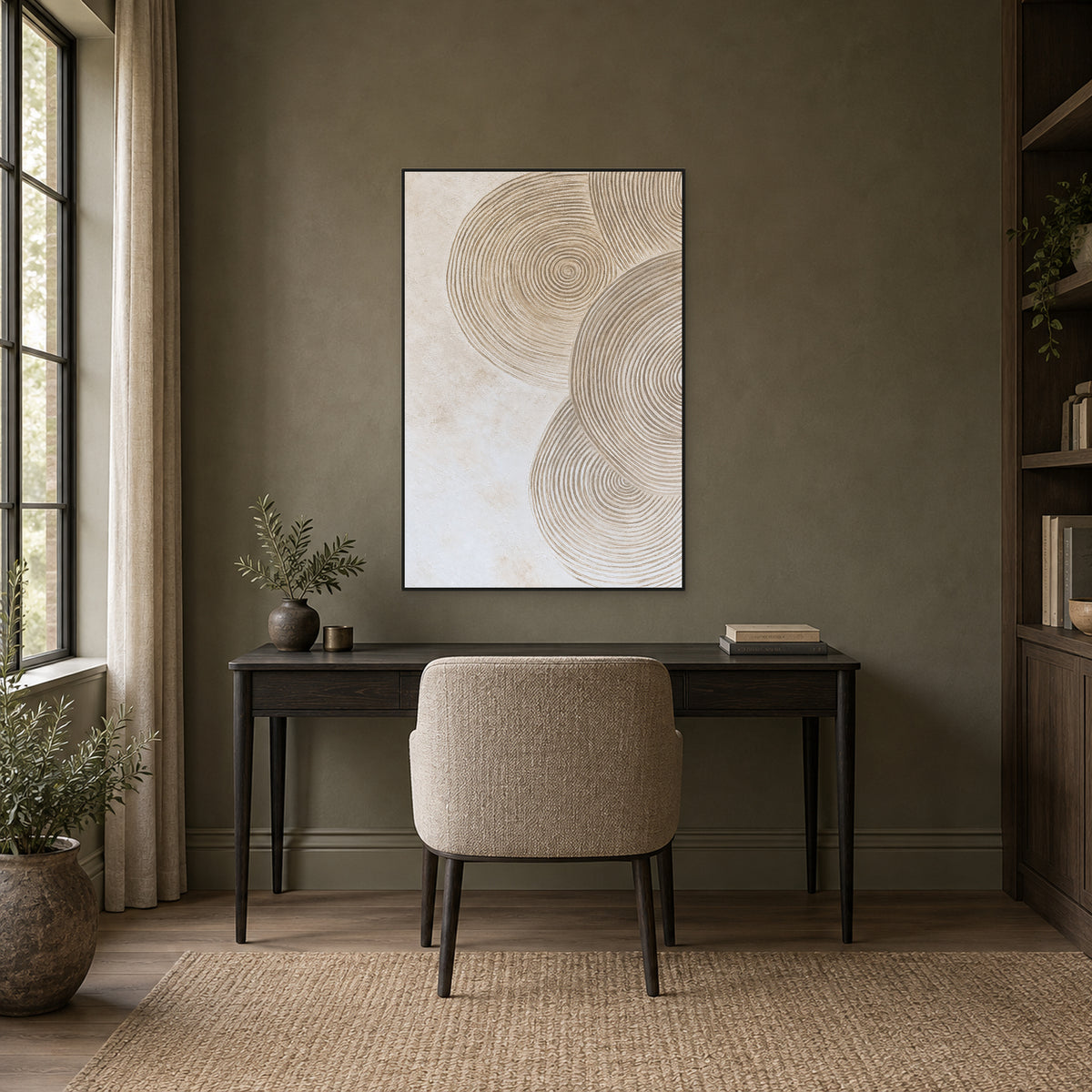 Concentric ring artwork in a black frame above a dark wooden desk against an olive-grey study wall.