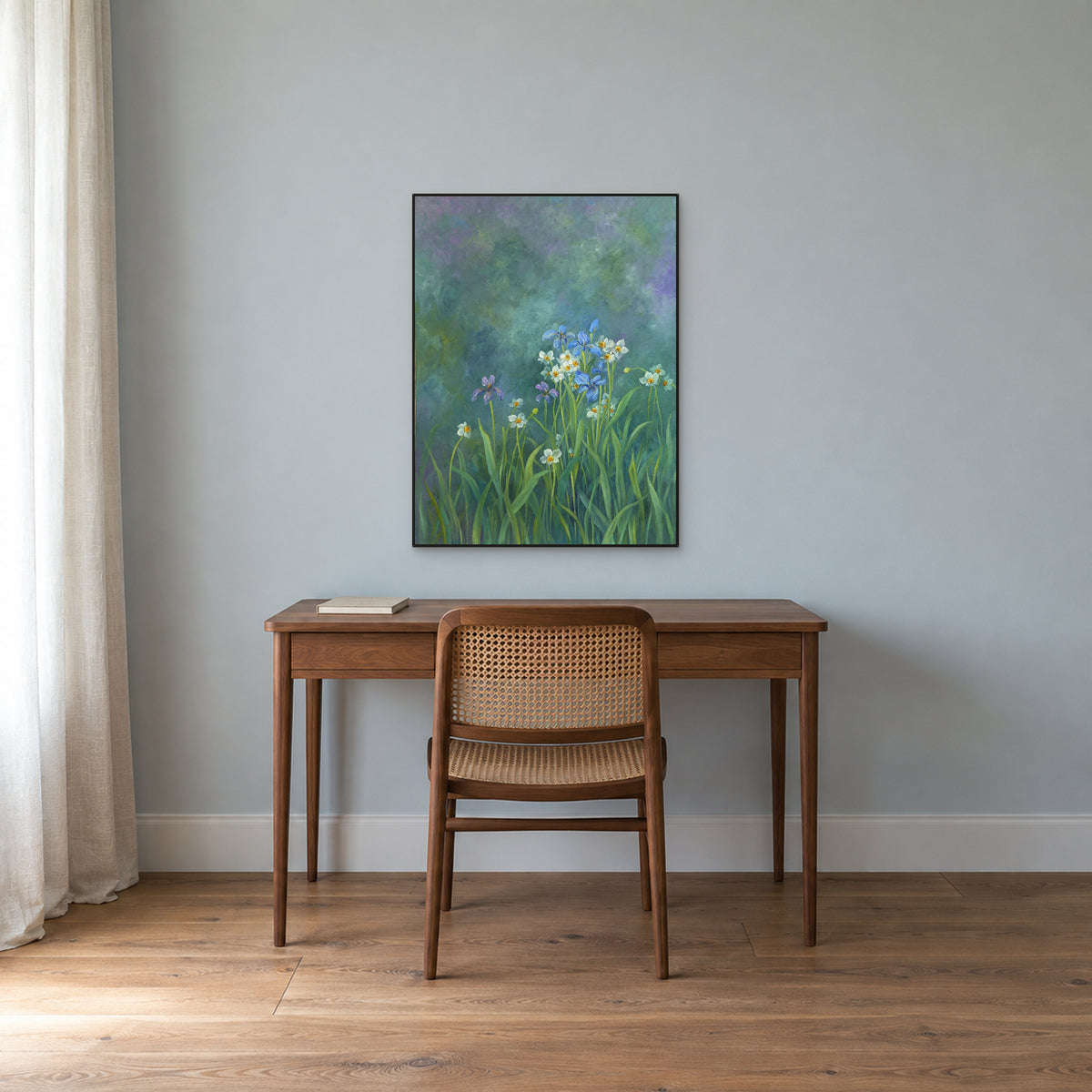 Blue irises and white flowers in a slim black frame above a walnut desk on a blue-grey wall