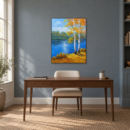 Blue river and golden birch painting in a slim black frame above a wooden desk