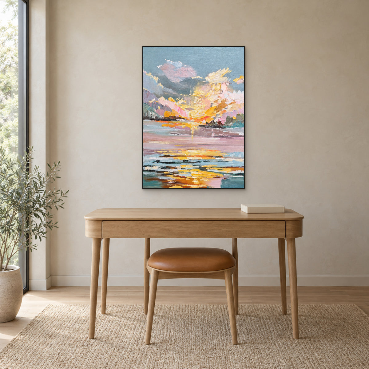 Pastel sunset and water reflections in a slim black frame above a light oak desk