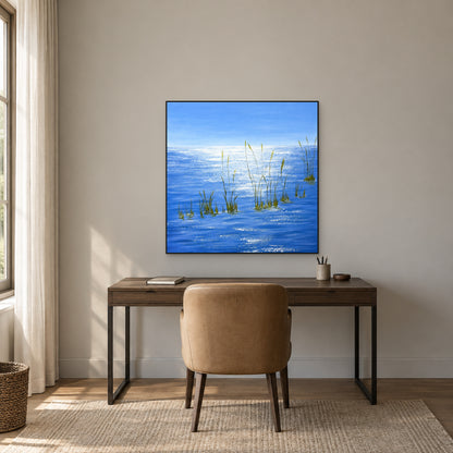 Paysage marin carré bleu dans un fin cadre noir au-dessus d’un bureau sombre et d’une chaise fauve