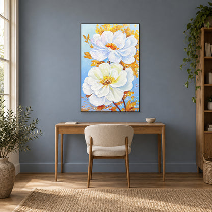 White floral painting in a thin black floating frame above a wooden desk against a muted blue wall.