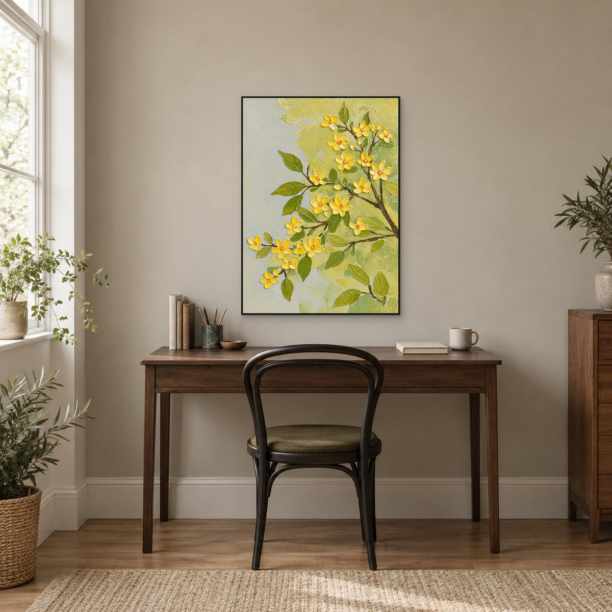 Tableau de fleurs jaunes dans un cadre noir, au-dessus d’un bureau en bois sombre près d’une fenêtre lumineuse