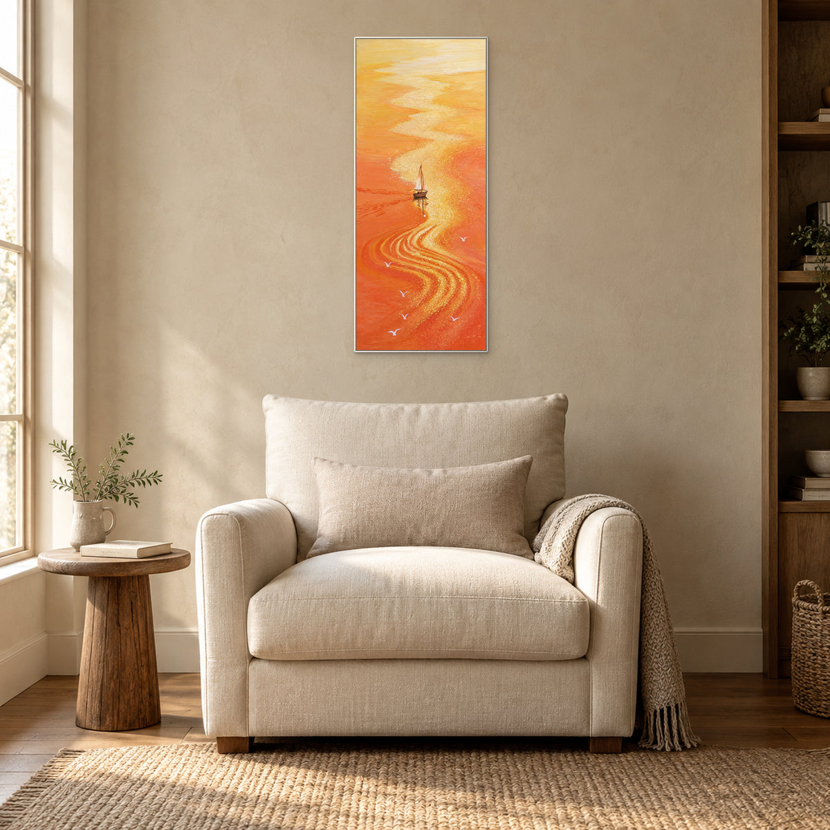 White-framed orange sailboat artwork above a cream armchair beside a sunlit window