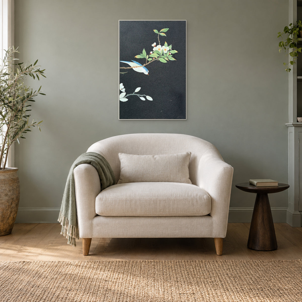 White-framed bird and flower artwork above an ivory armchair on a muted green wall