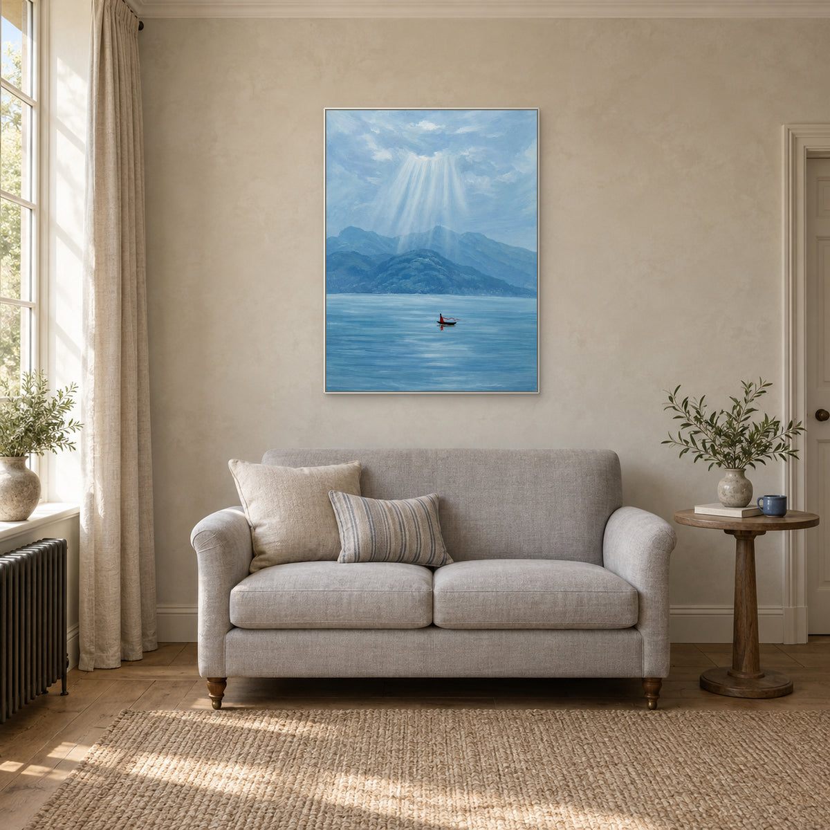 Vertical boat and blue lake artwork in a white floating frame above a small pale sofa in a reading corner