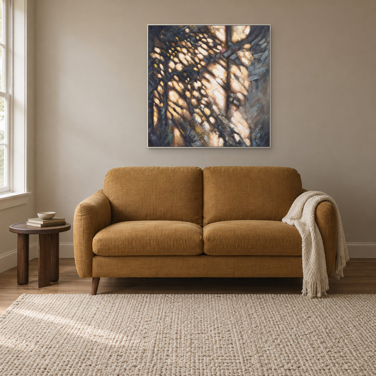 Textured light-and-shadow abstract in a white floating frame above an ochre reading sofa