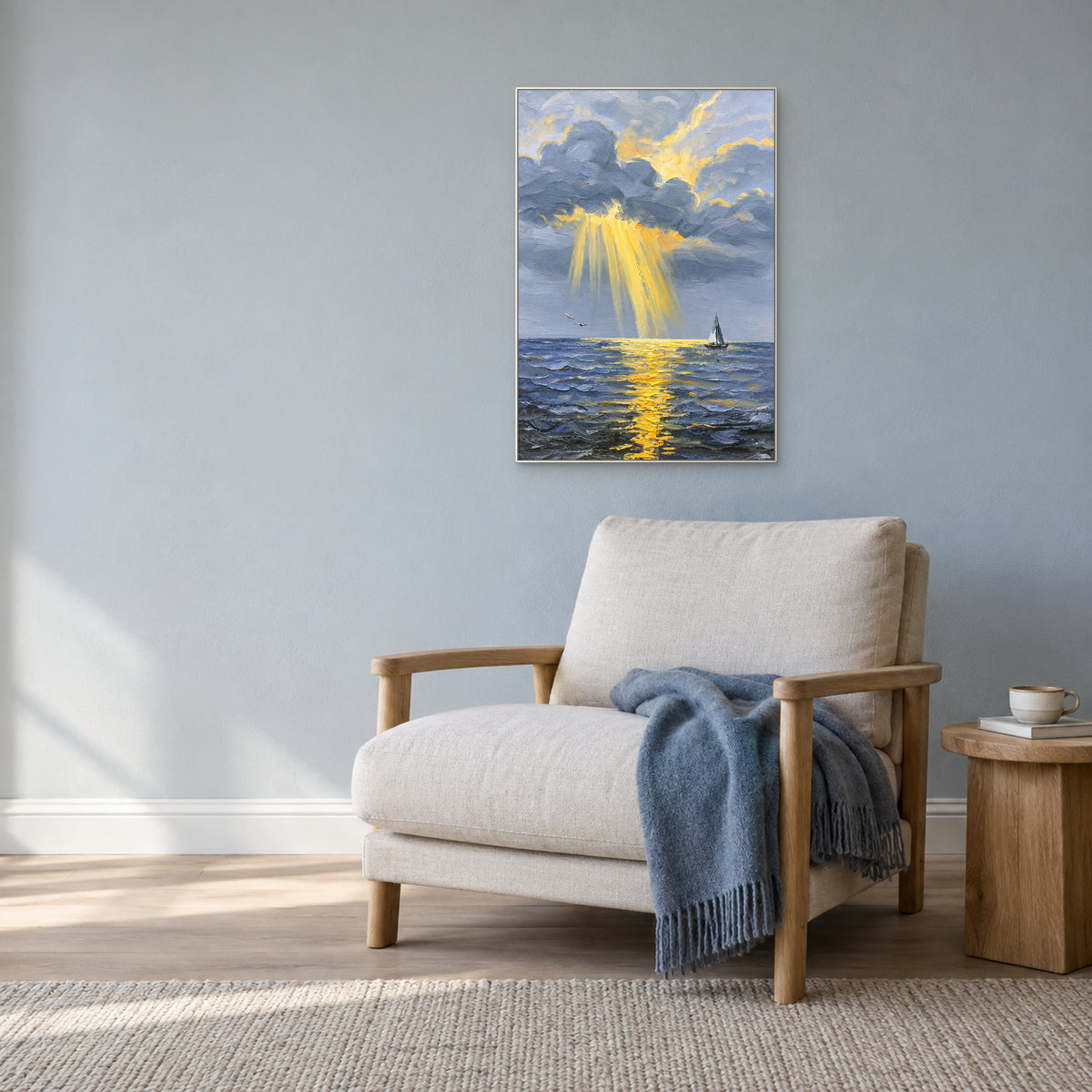 Hand-painted blue seascape in a white frame above an ivory lounge chair against a blue-grey wall.