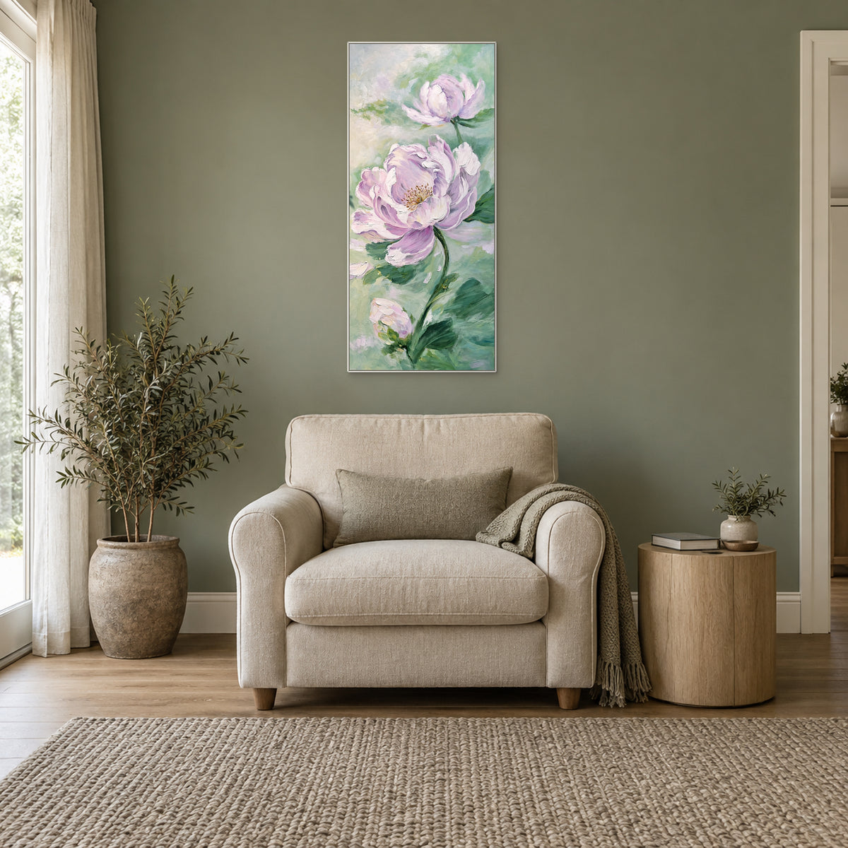 Tall lilac peony painting in a white floating frame centred above a cream armchair against a sage wall