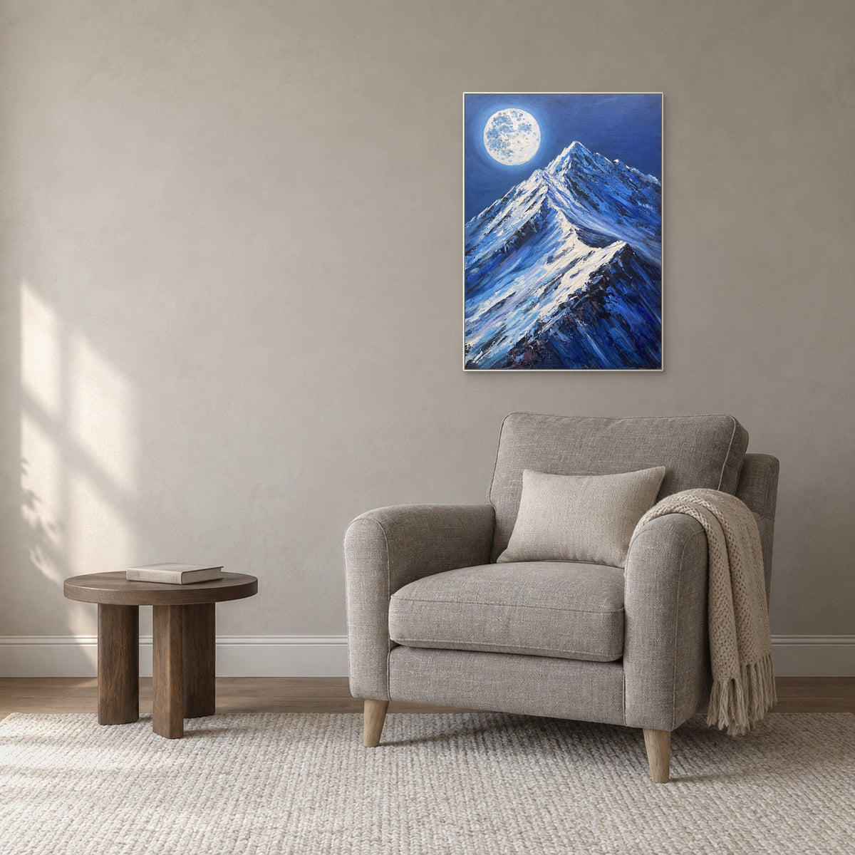 Paysage de montagne nocturne bleu dans un cadre blanc, au-dessus d’un fauteuil de lecture gris
