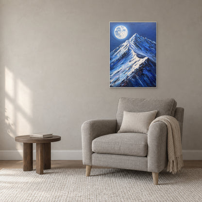 Paysage de montagne nocturne bleu dans un cadre blanc, au-dessus d’un fauteuil de lecture gris