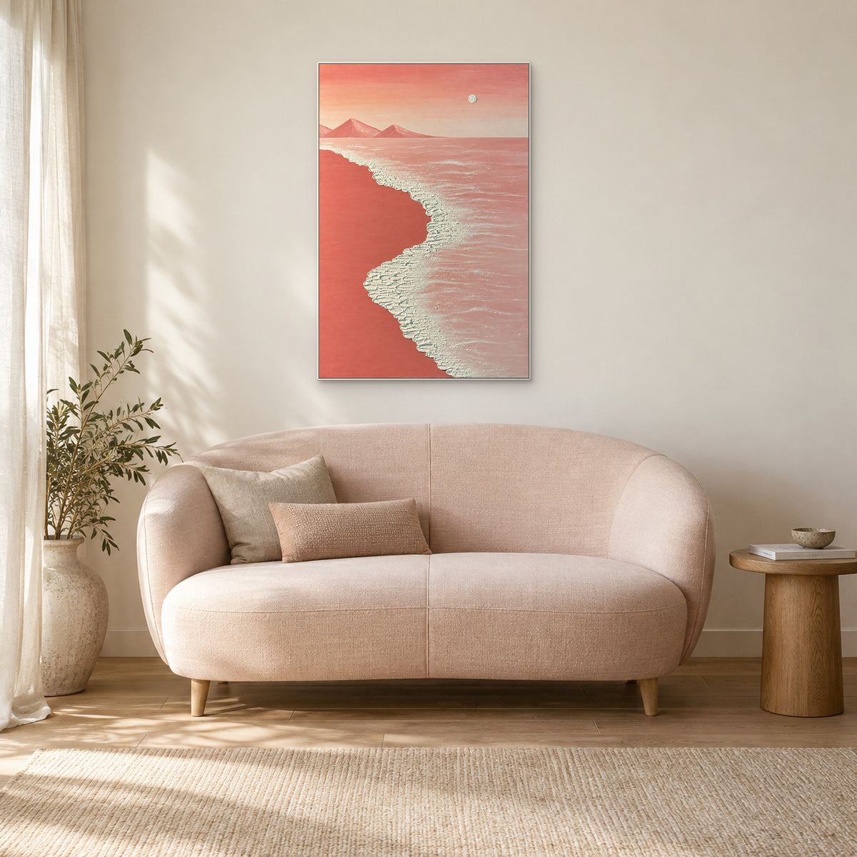 Textured coral-pink seascape in a white floating frame above a curved pale pink sofa in a reading corner