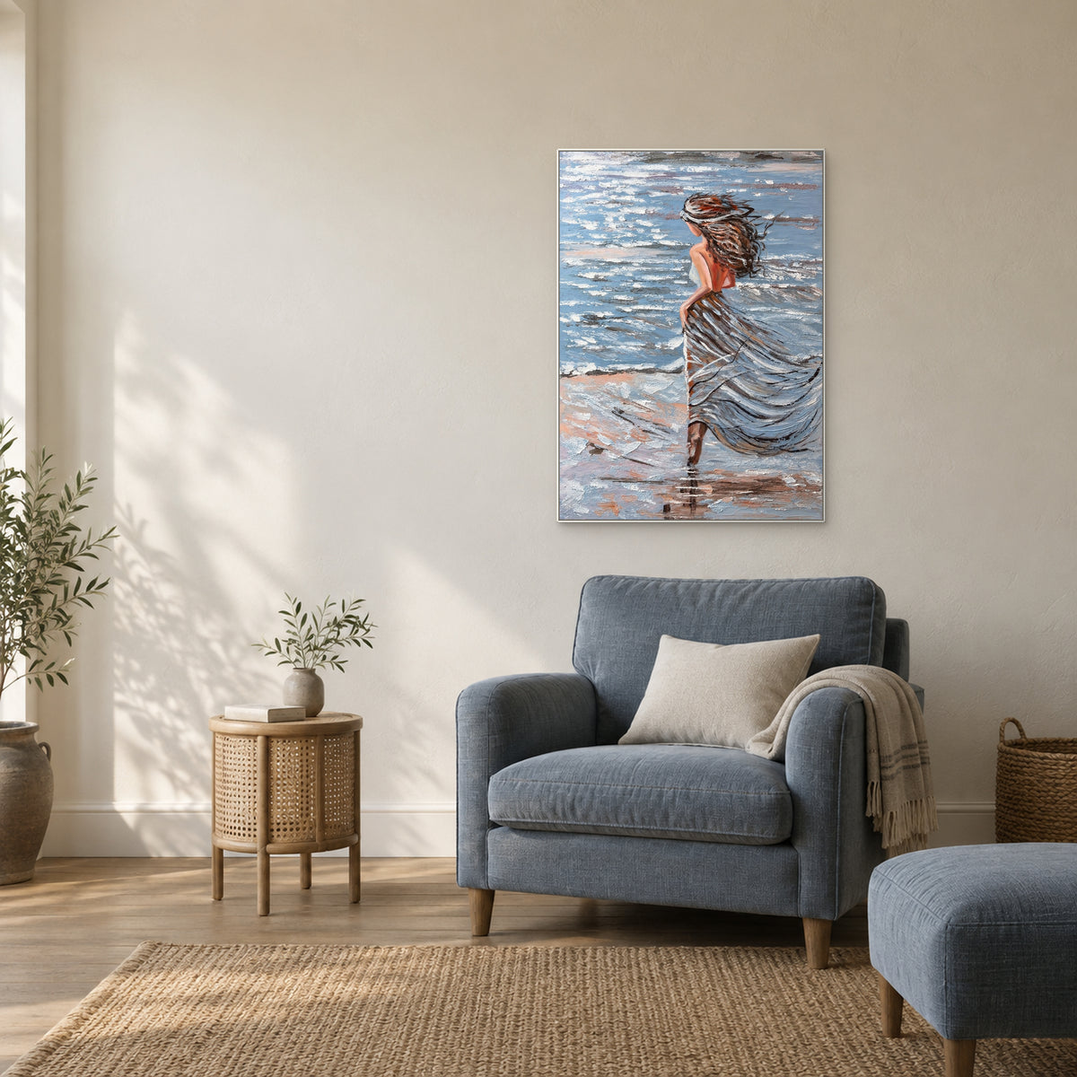 Portrait côtier vertical dans un cadre flottant blanc, au-dessus d'un fauteuil bleu ardoise près d'une table d'appoint ronde tressée