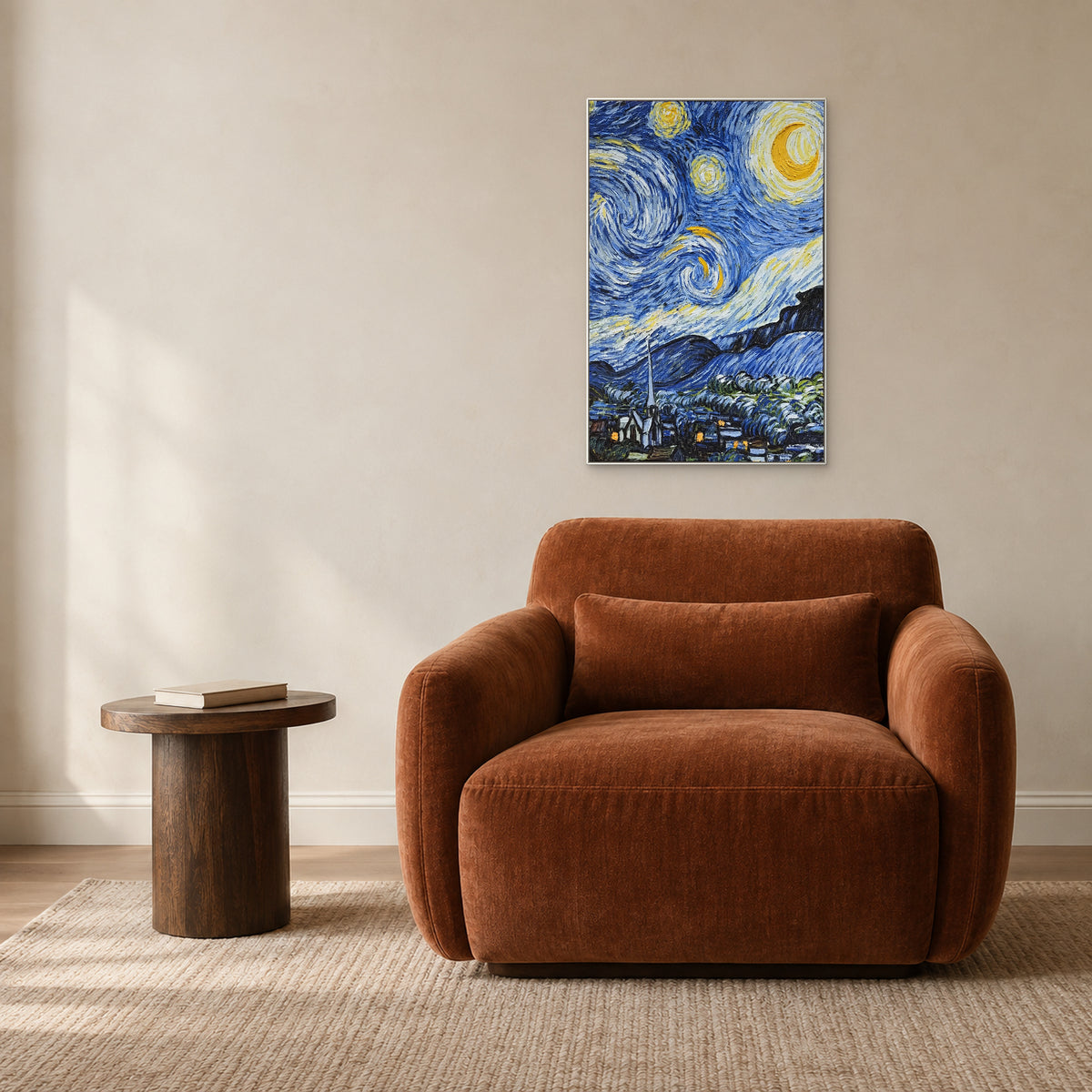 Tableau nocturne bleu et jaune dans un cadre blanc au-dessus d’un fauteuil rouille, près d’une petite table en bois.