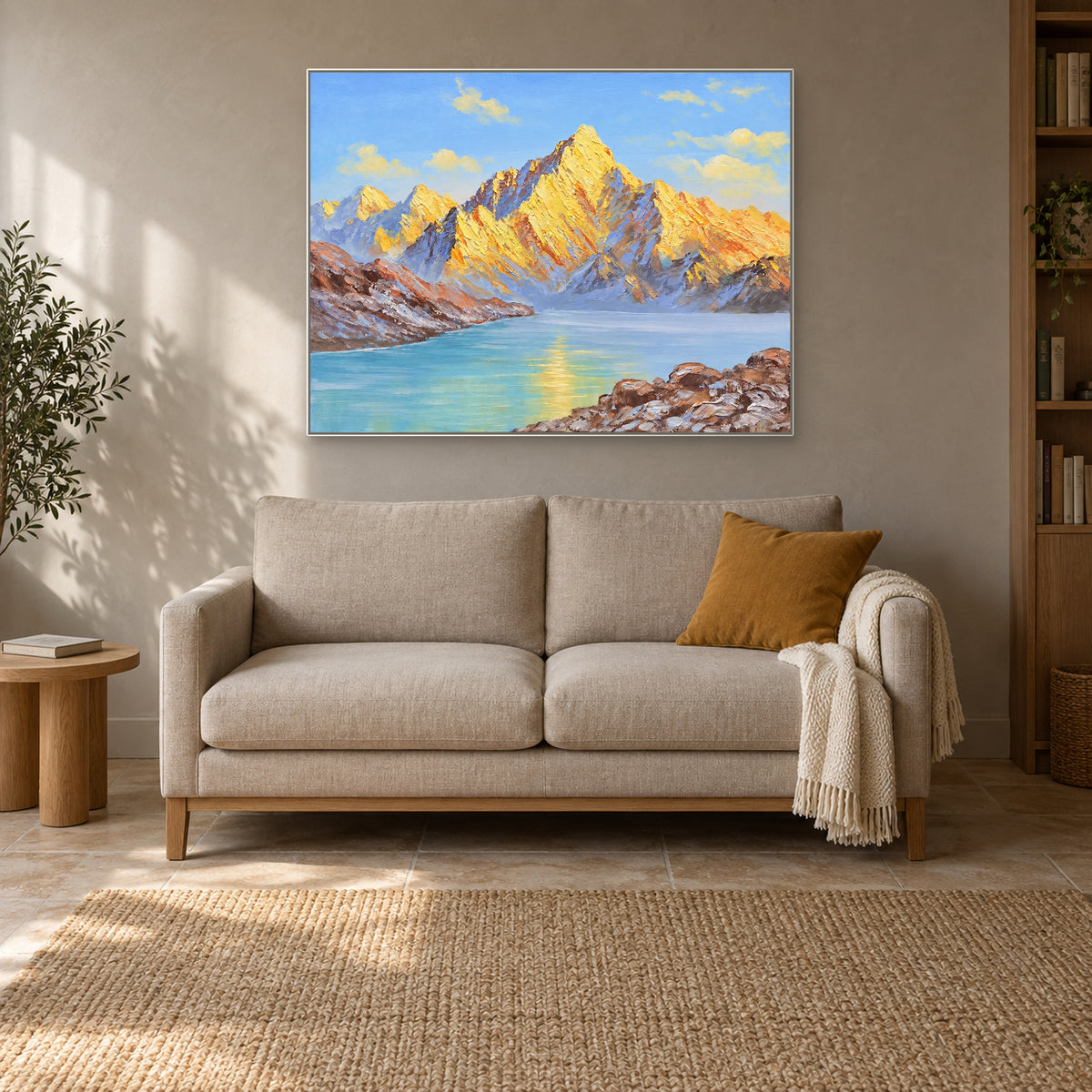 Paysage de montagnes et de lac encadré de blanc, au-dessus d'un petit canapé crème avec un coussin ocre