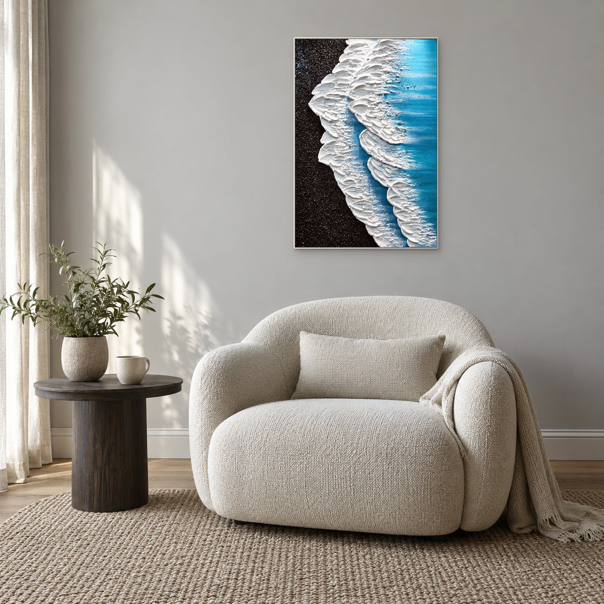 Textured white surf painting framed in white above a rounded cream armchair