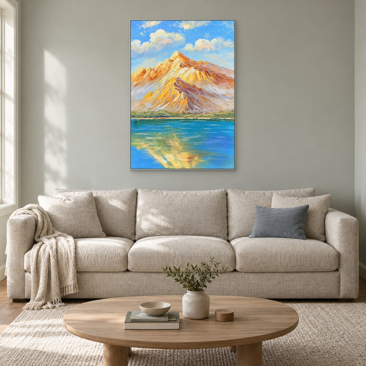 Paysage vertical de montagnes ambrées dans un cadre argenté, au-dessus d'un canapé écru sur un mur gris sauge