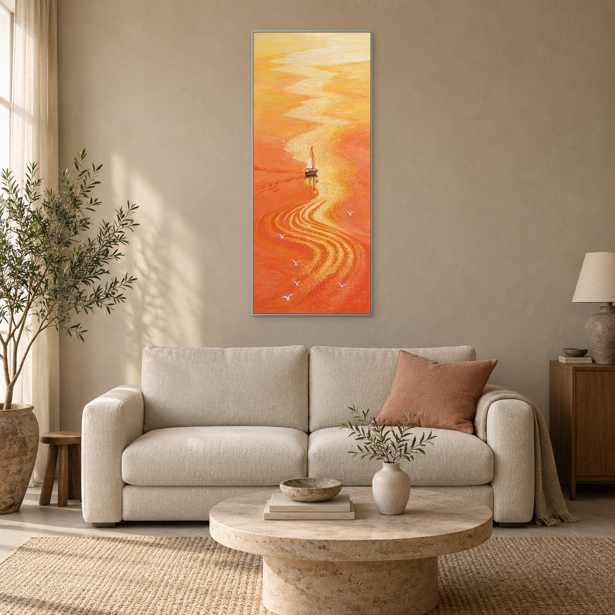 Orange sea and golden reflection in a silver-tone frame above a cream sofa with a muted coral cushion