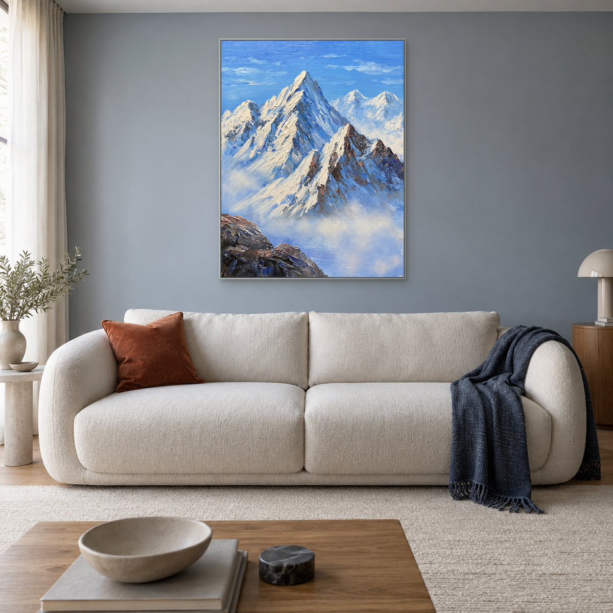 Blue Summit painting with a silver-tone frame above an ivory living-room sofa