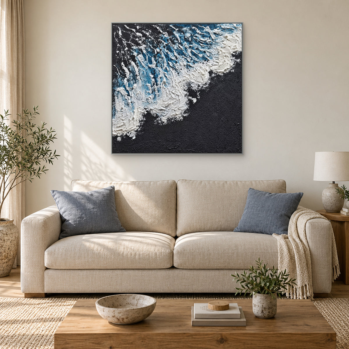 Blue and charcoal square wave painting in a silver-tone frame above an oatmeal sofa with blue-grey cushions