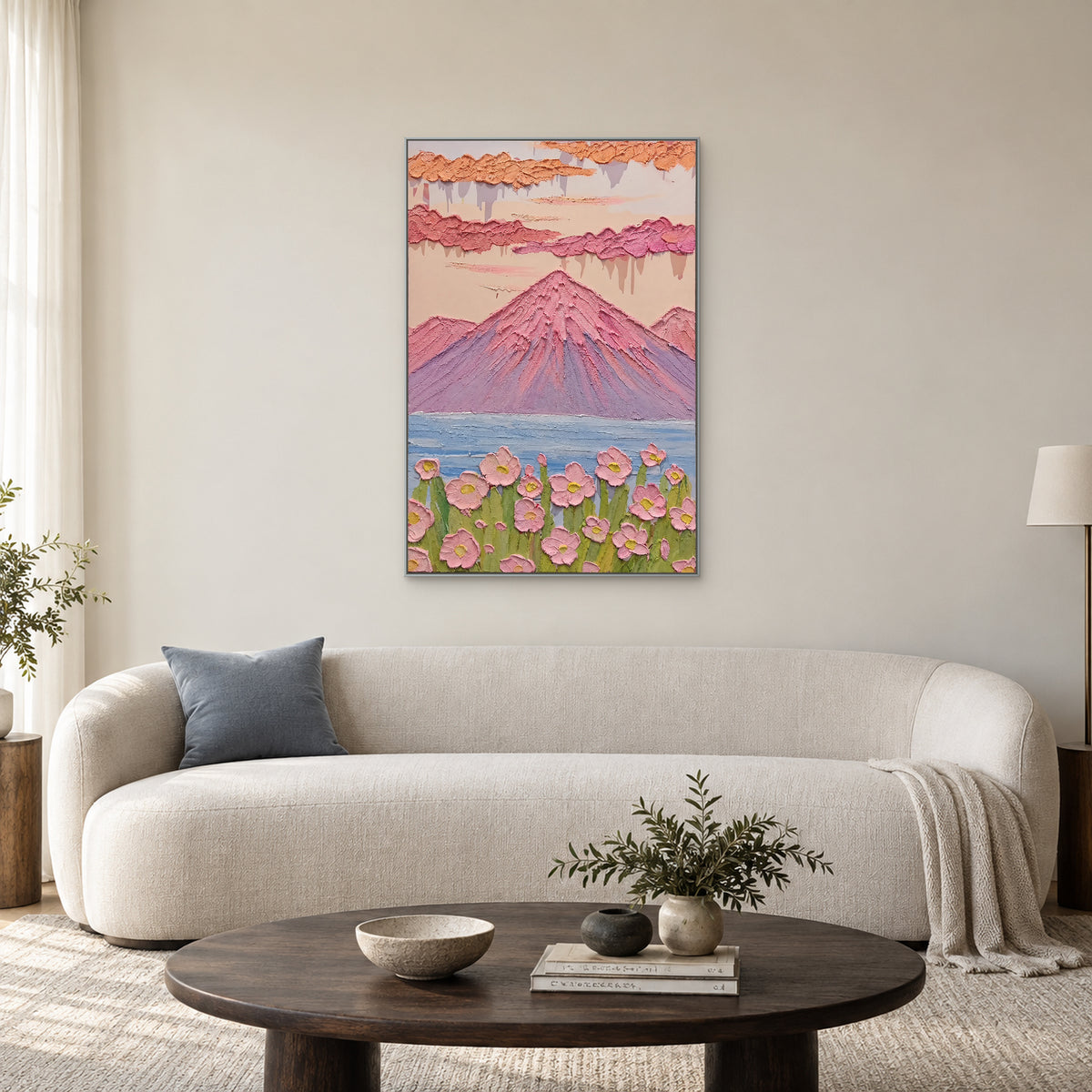 Tableau vertical de montagne pastel dans un cadre argenté au-dessus d’un canapé ivoire aux lignes courbes