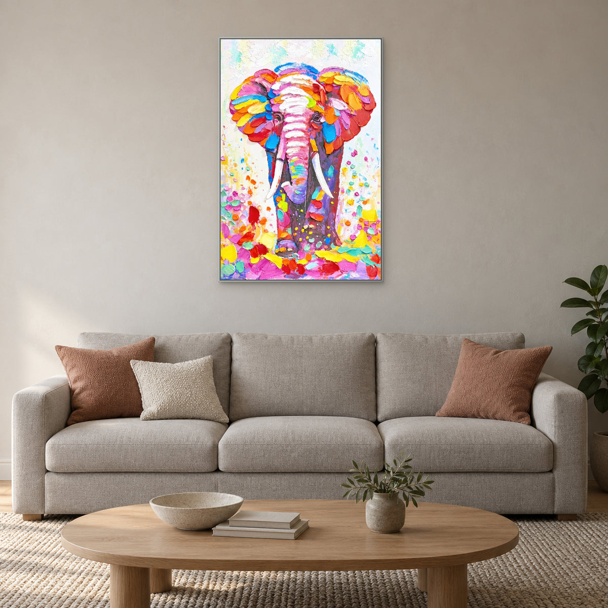 Éléphant multicolore dans un cadre argenté au-dessus d’un canapé clair aux coussins terracotta