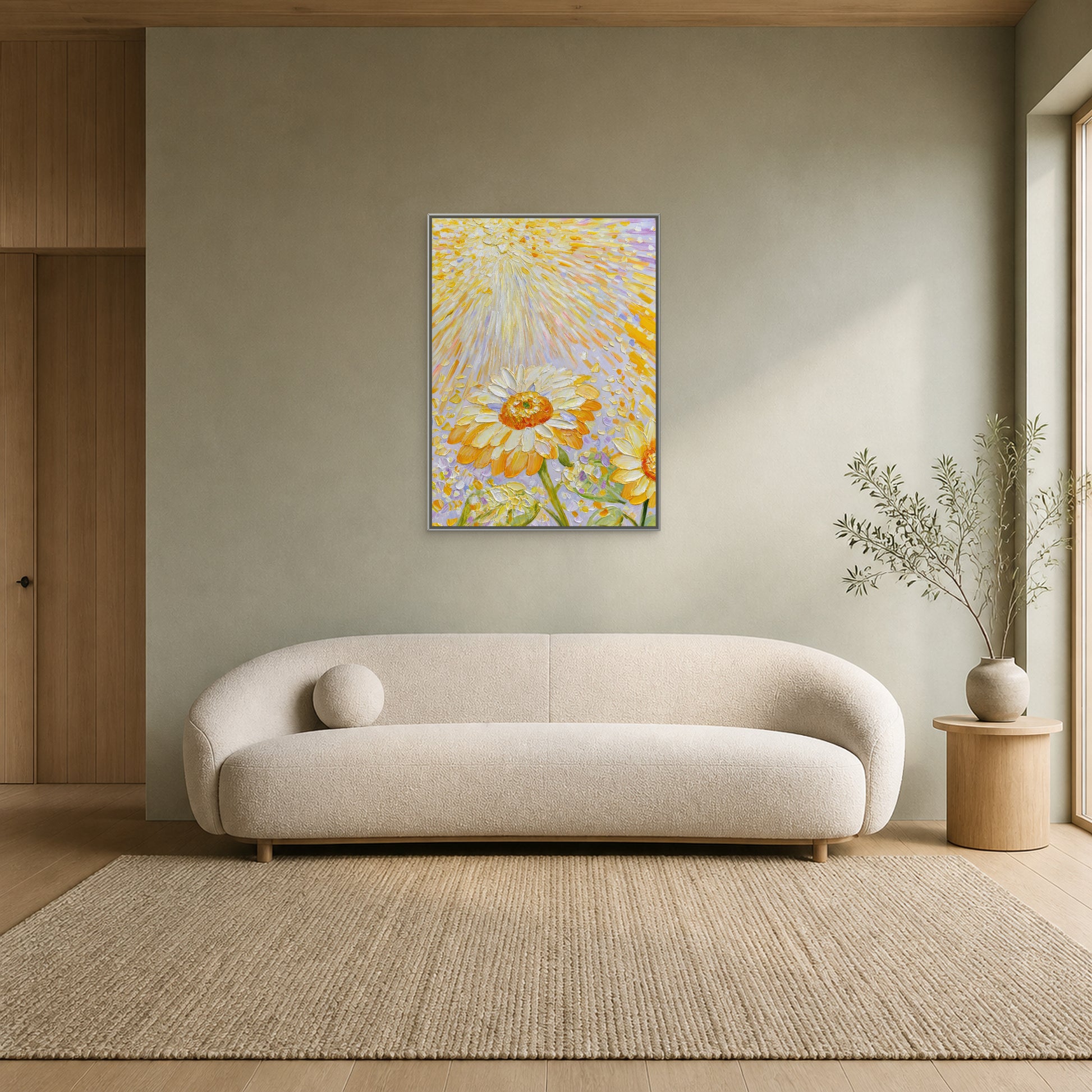 Sunflowers in Golden Light in a slim silver floating frame centred above a curved cream sofa on a pale sage wall