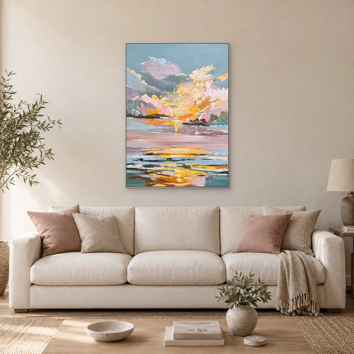 Pink and gold sunset landscape in a silver-tone frame above a cream sofa
