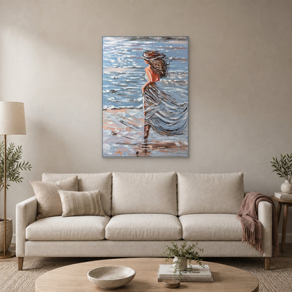 Tableau Brise marine dans un cadre flottant argenté, centré au-dessus d'un canapé ivoire avec un plaid rose poudré