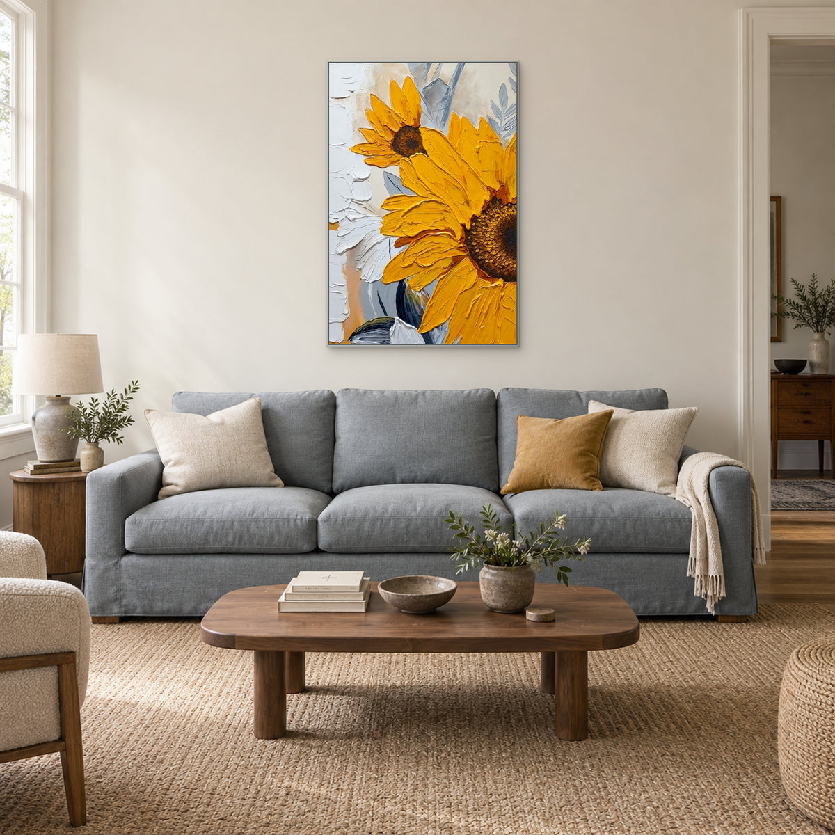 Yellow sunflower artwork in a silver-tone frame centred above a grey-blue sofa with cream and ochre cushions